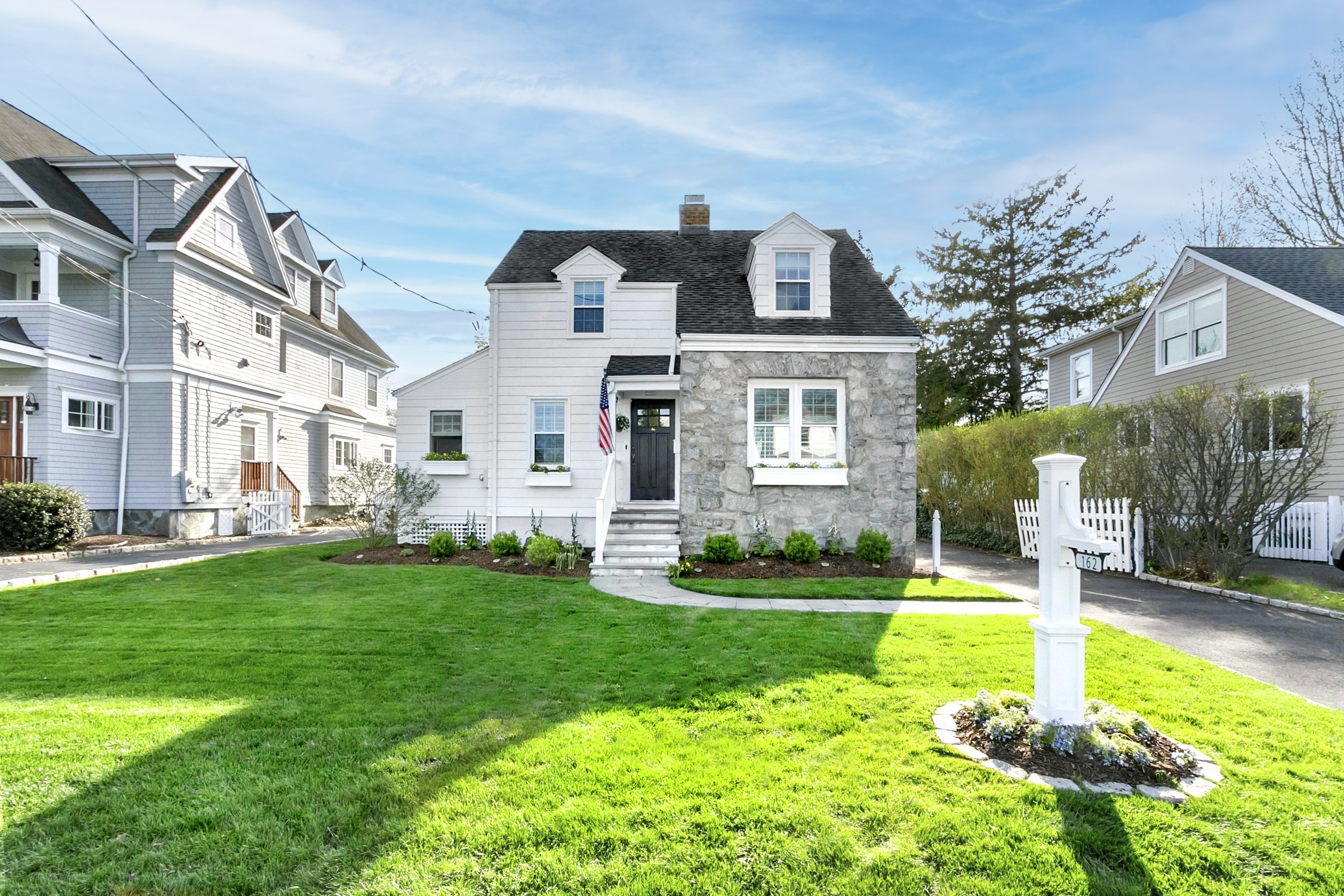 White Cape-style home with dark shutters and a manicured front lawn at 162 Eastlawn Street, Fairfield CT