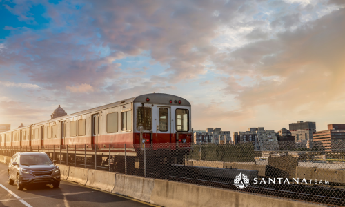 Boston Red Line train passing alongside cars during morning commute with city skyline in the background
