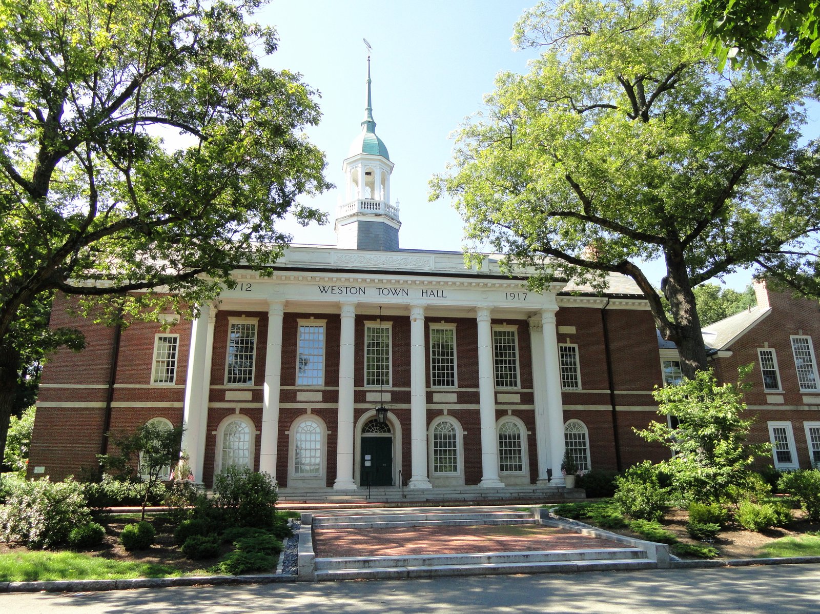 Historic Town Hall in Weston, Massachusetts, with brick facade, white trim, and surrounding trees