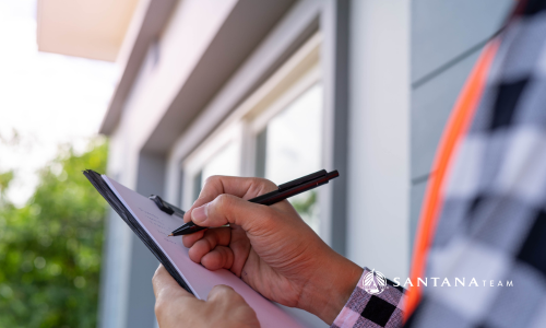 Home inspector writing notes on a clipboard outside a Greater Boston house