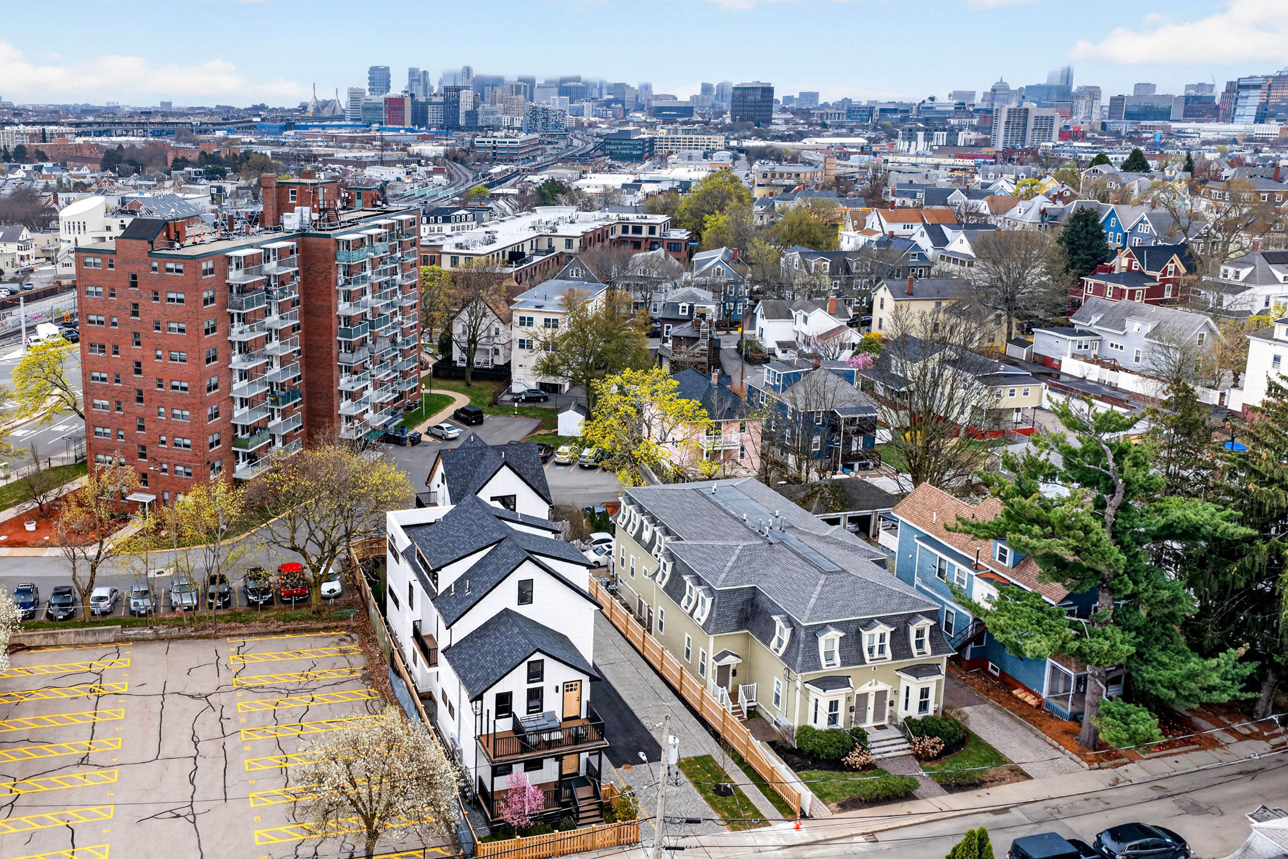Aerial view of a Greater Boston residential neighborhood with a mix of homes and city skyline, used for a spring 2026 real estate market update