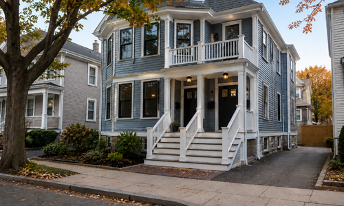 Exterior of a two-family home converted into condominiums in Somerville, Massachusetts, shown in a late-October residential setting.