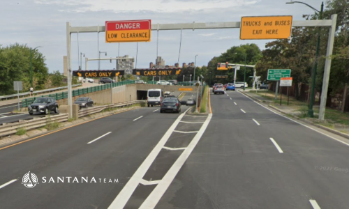 Roadside signs on Soldiers Field Road in Boston warning “Danger Low Clearance – Cars Only” with an arrow and “Trucks and Buses Exit Here,” directing drivers to avoid the low overpass.