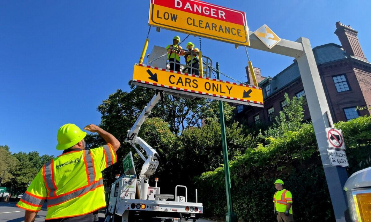 DCR workers installing low-clearance and Cars Only warning signs near Storrow Drive in Boston ahead of September moving season.