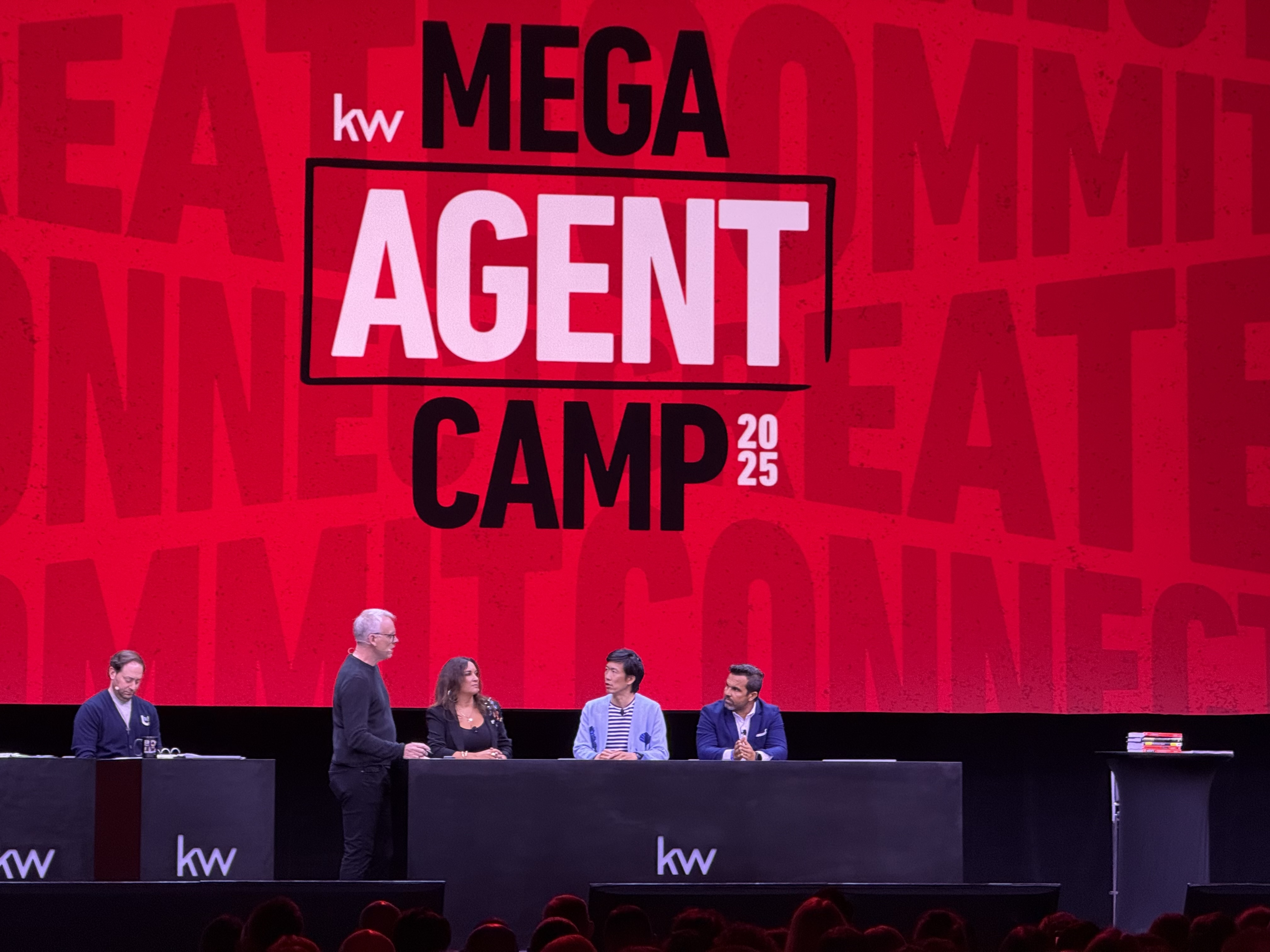 Hudson Santana speaking on the main stage at KW Mega Agent Camp 2025, wearing a blue blazer and white shirt