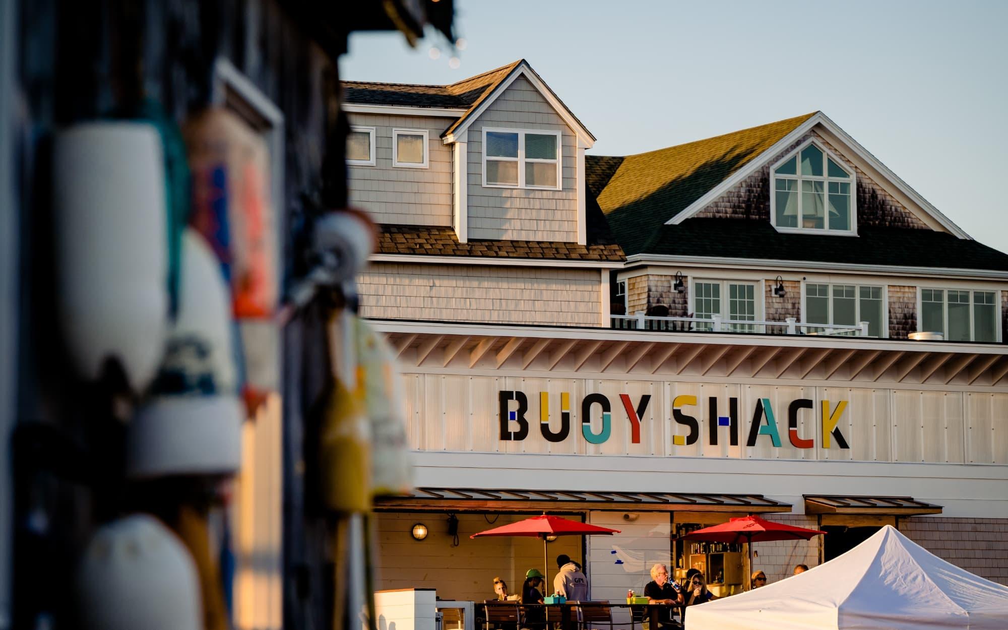 Outdoor waterfront dining at Buoy Shack in Kittery, Maine with seafood, drinks, and scenic harbor views.