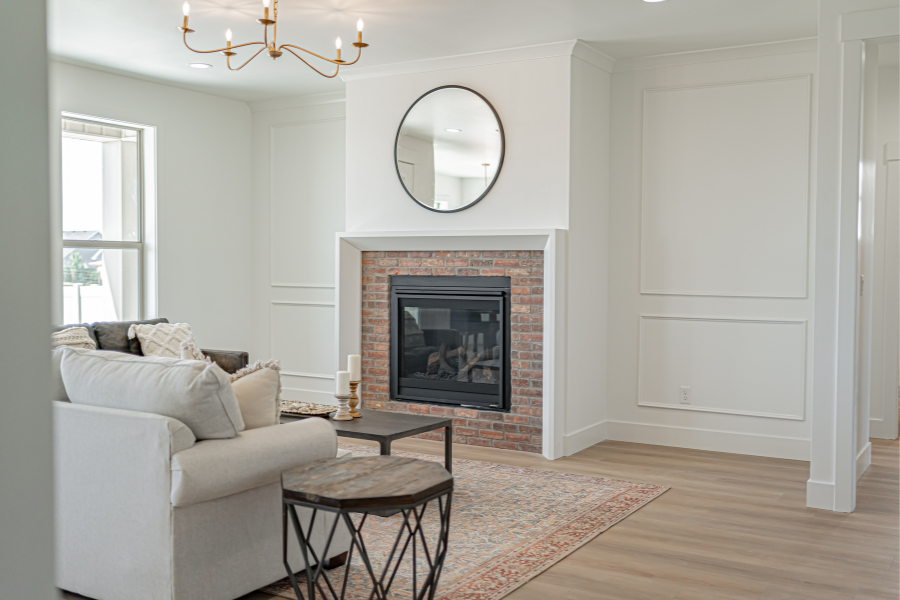 Bright open-concept living room featuring a brick fireplace, custom wall trim, luxury vinyl flooring, and modern farmhouse design.