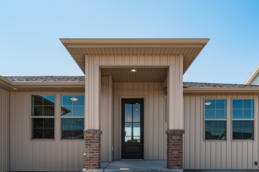 Modern single-story home exterior with covered front entry, vertical siding, brick columns, and contemporary architectural details in Idaho Falls, Idaho.