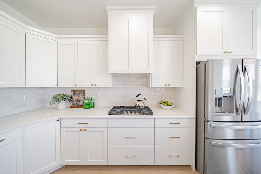 White shaker-style kitchen with stainless steel appliances, custom cabinetry, quartz countertops, and a spacious open layout.