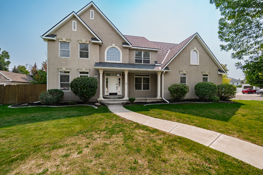 Two-story beige home with landscaped front yard and curved walkway in Idaho Falls neighborhood