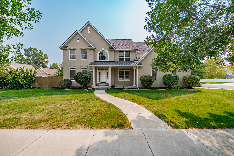 Front exterior of two-story Idaho Falls home with large windows, manicured lawn, and inviting entryway
