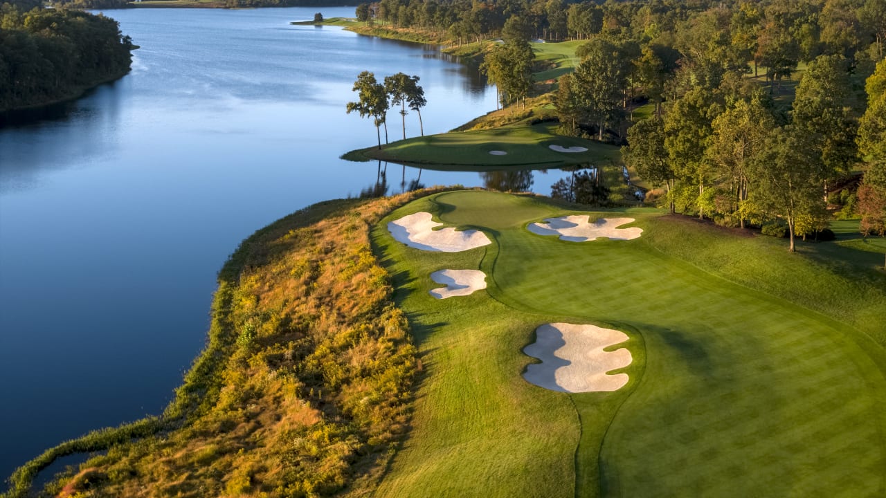 Aerial view of the Robert Trent Jones Golf Club golf course in Gainesville, Virginia, featuring lush greens, bunkers, trees, and adjacent scenic water.