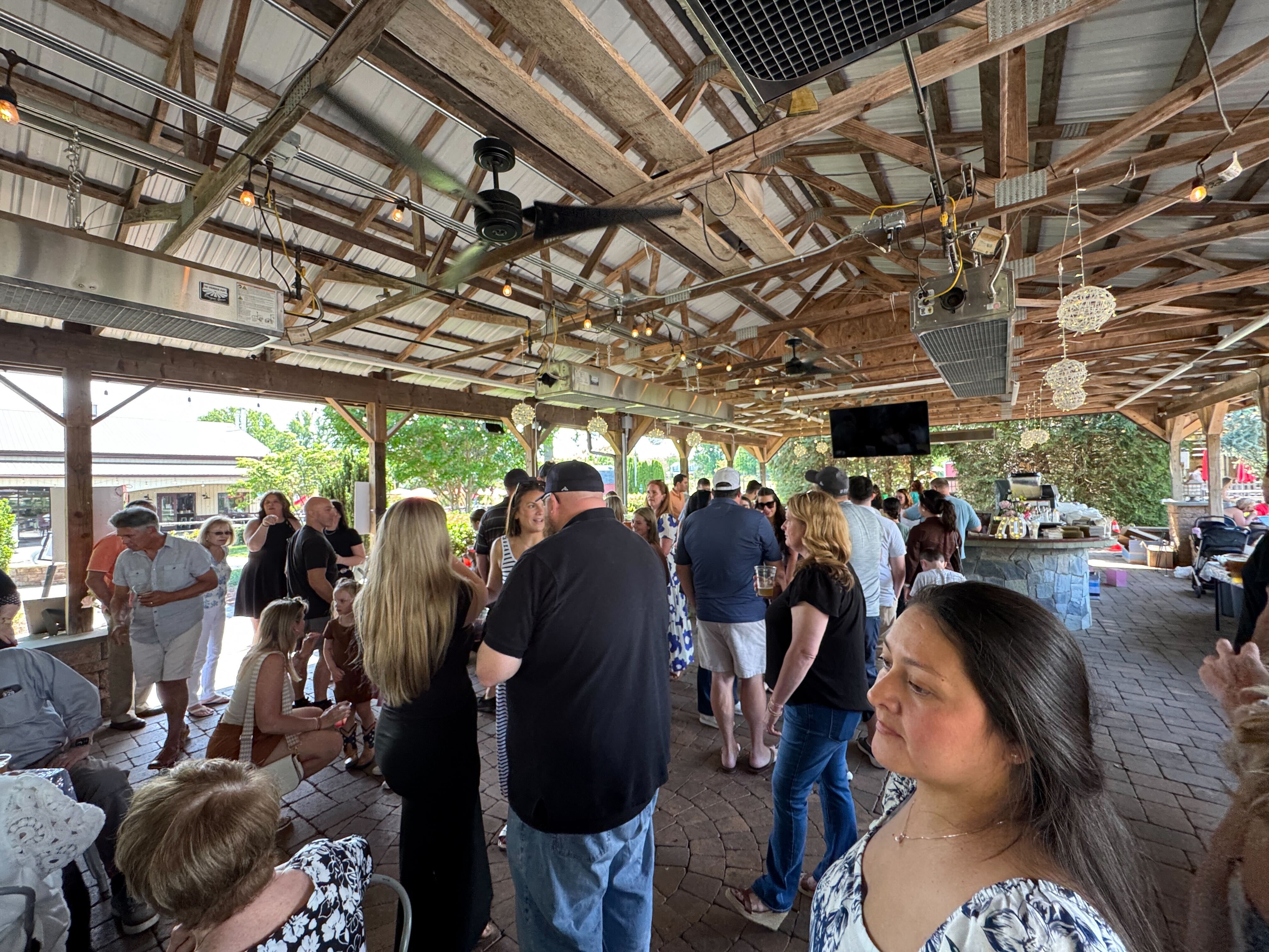 A large, happy crowd gathered under a covered outdoor patio at The Farm Brewery at Broad Run, enjoying a summer movie night event in Northern Virginia.