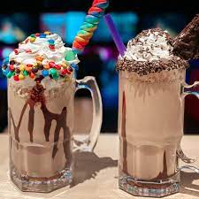 Two indulgent "stacked shakes" from the PINSTACK restaurant menu, featuring elaborate candy and chocolate toppings, a signature dessert at the new Loudoun County location.