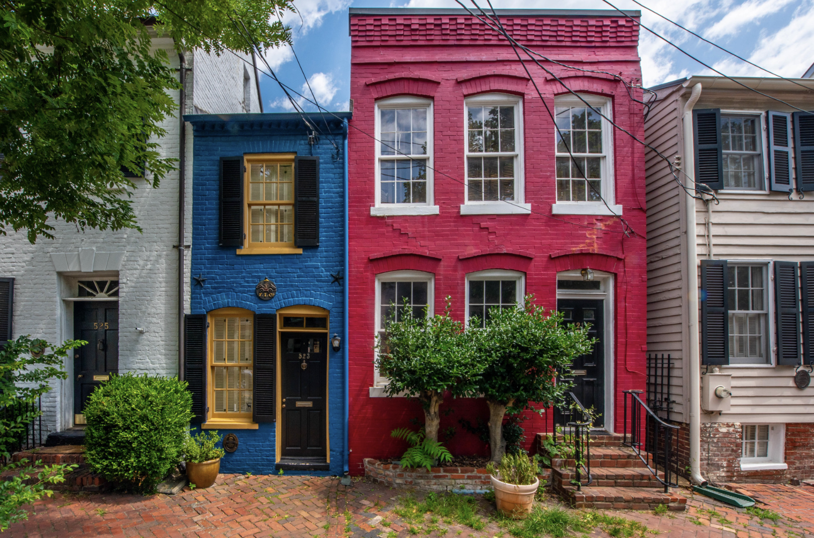 Colorful historic row houses in Old Town Alexandria, with a vibrant blue and red brick exterior on a charming cobblestone street.