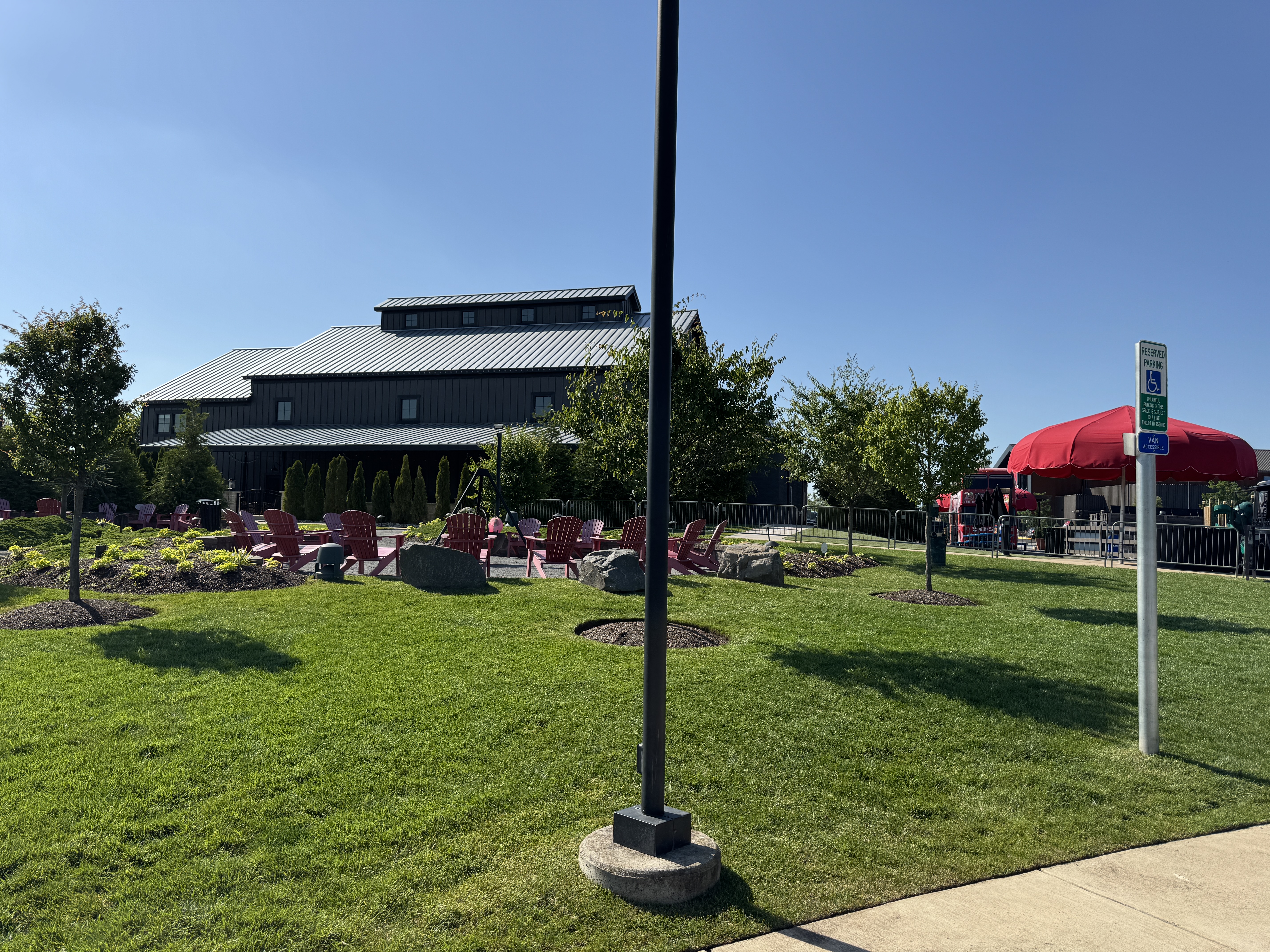 The spacious outdoor patio and lawn at the new MurLarkey Distillery, with red adirondack chairs for guests.
