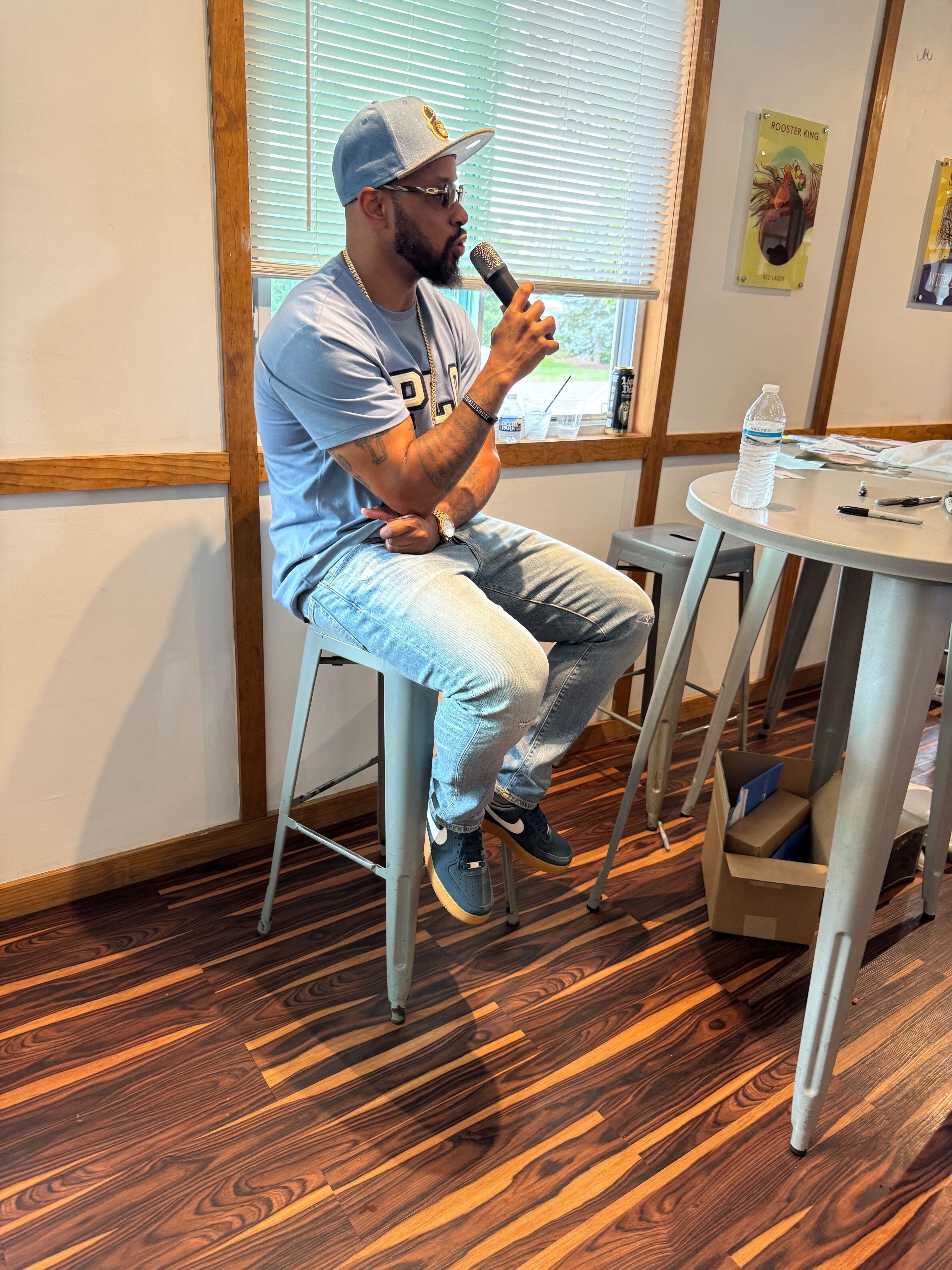 Former Washington football star Santana Moss speaking into a microphone during a Q&A session at the Colgan Team client appreciation event.
