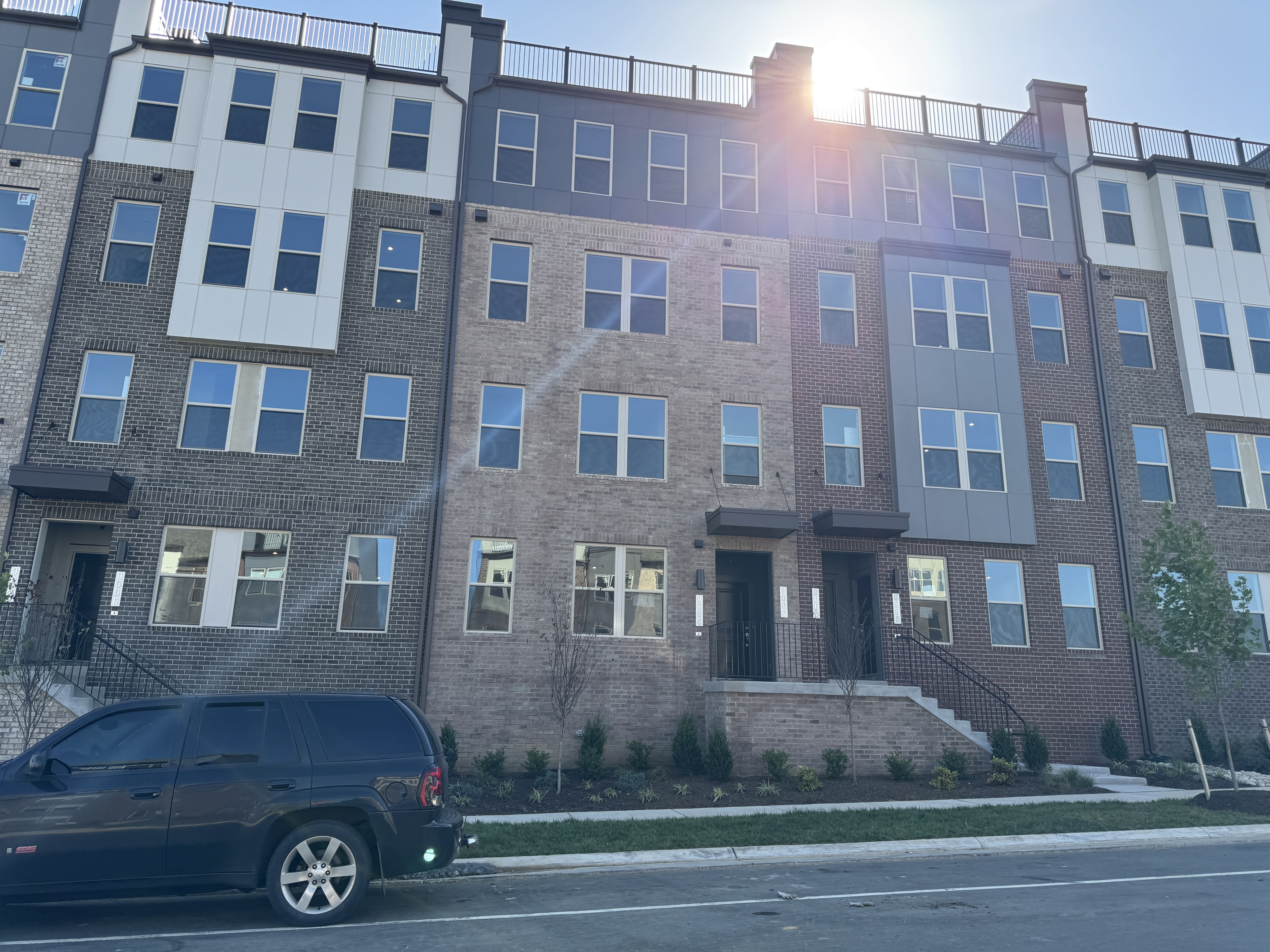 A sunlit row of modern, multi-story brick townhomes with large windows at the Innovation Center in Manassas, VA.