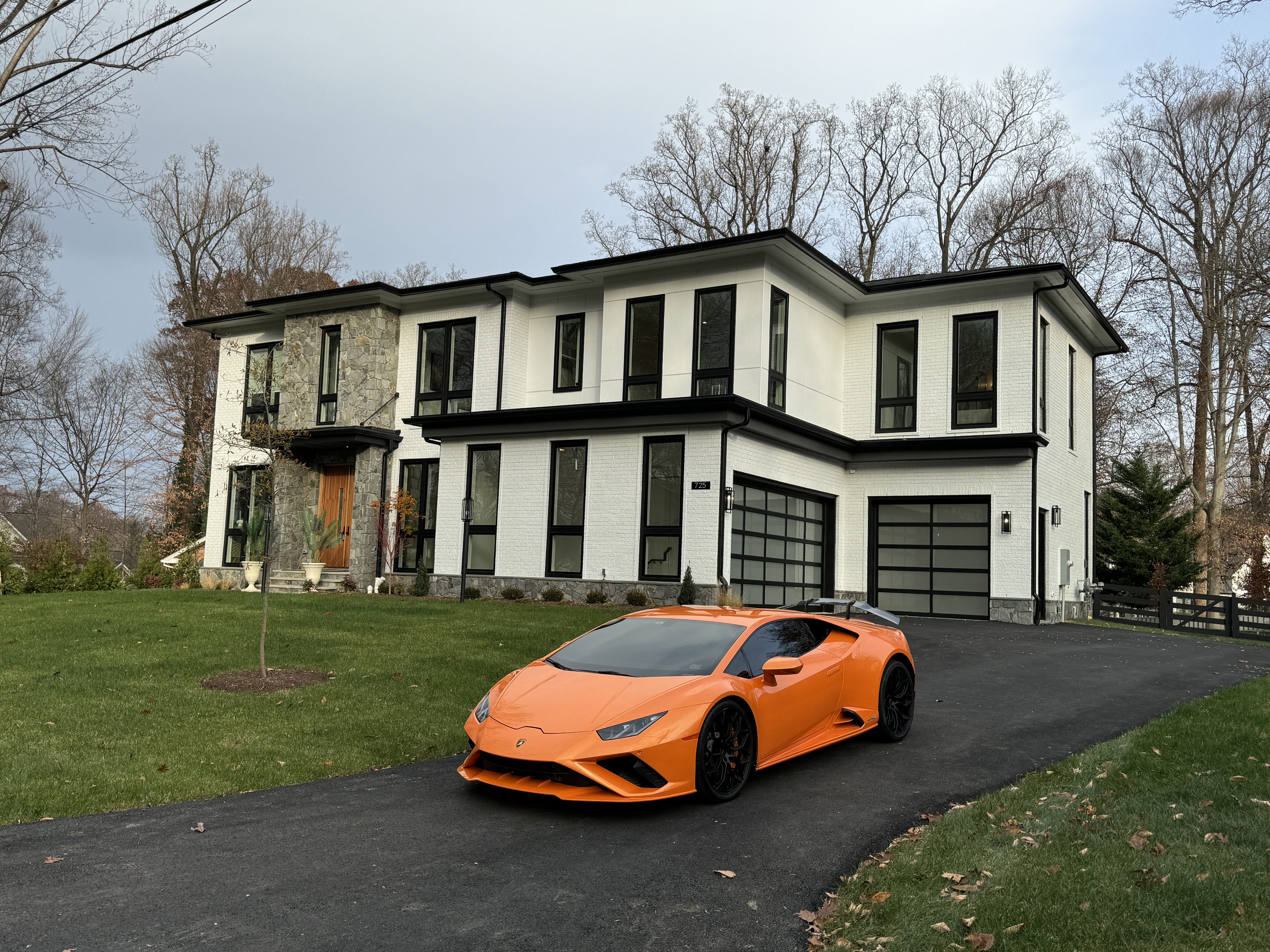A modern luxury home in McLean, VA, part of Fairfax County, with an orange Lamborghini in the driveway, showcasing the high-end real estate available as D.C. metro home prices reach record highs.