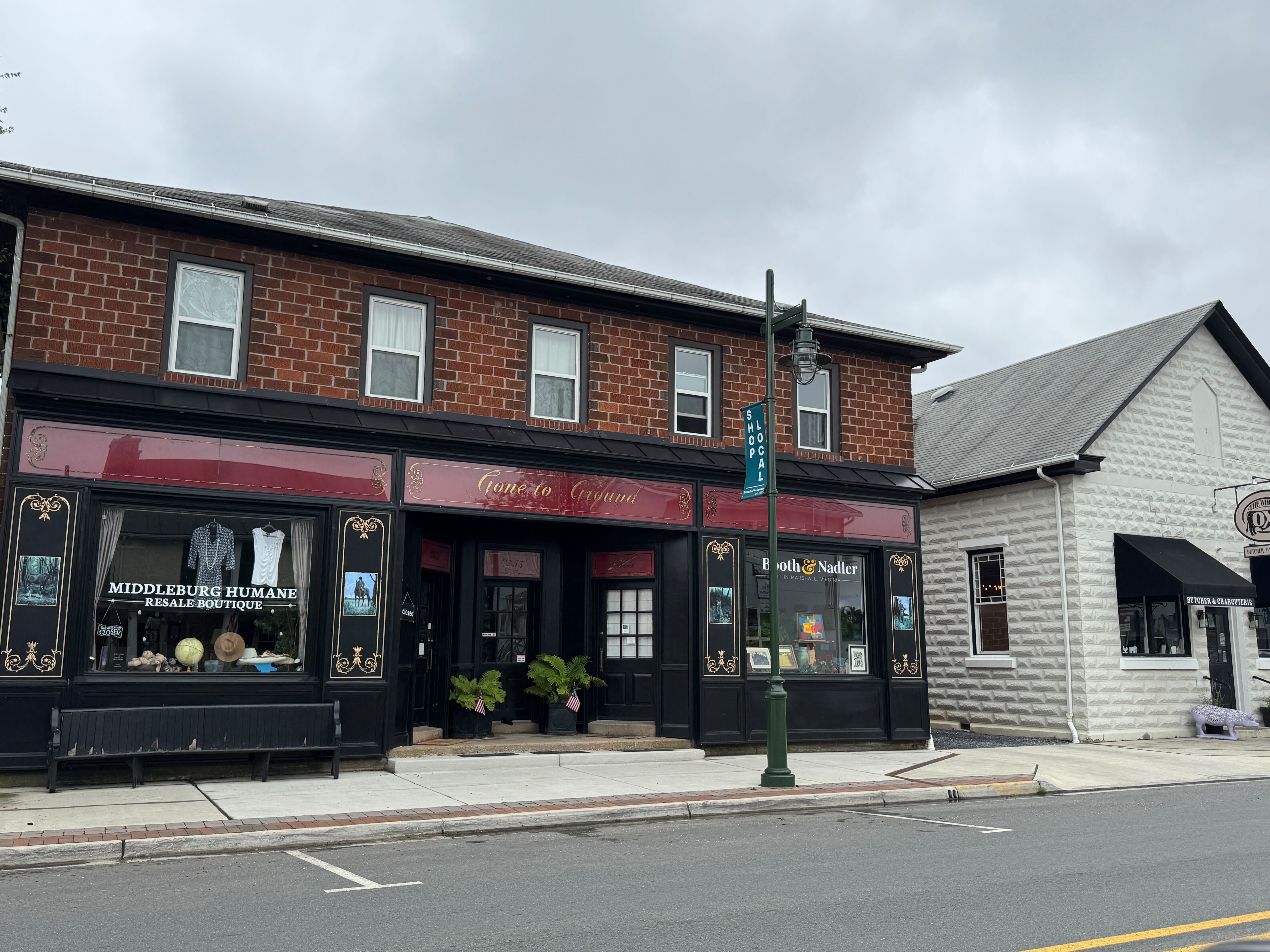 A street-level view of the historic brick storefronts in downtown Middleburg, VA, including the Middleburg Humane Resale Boutique and Booth & Nadler.