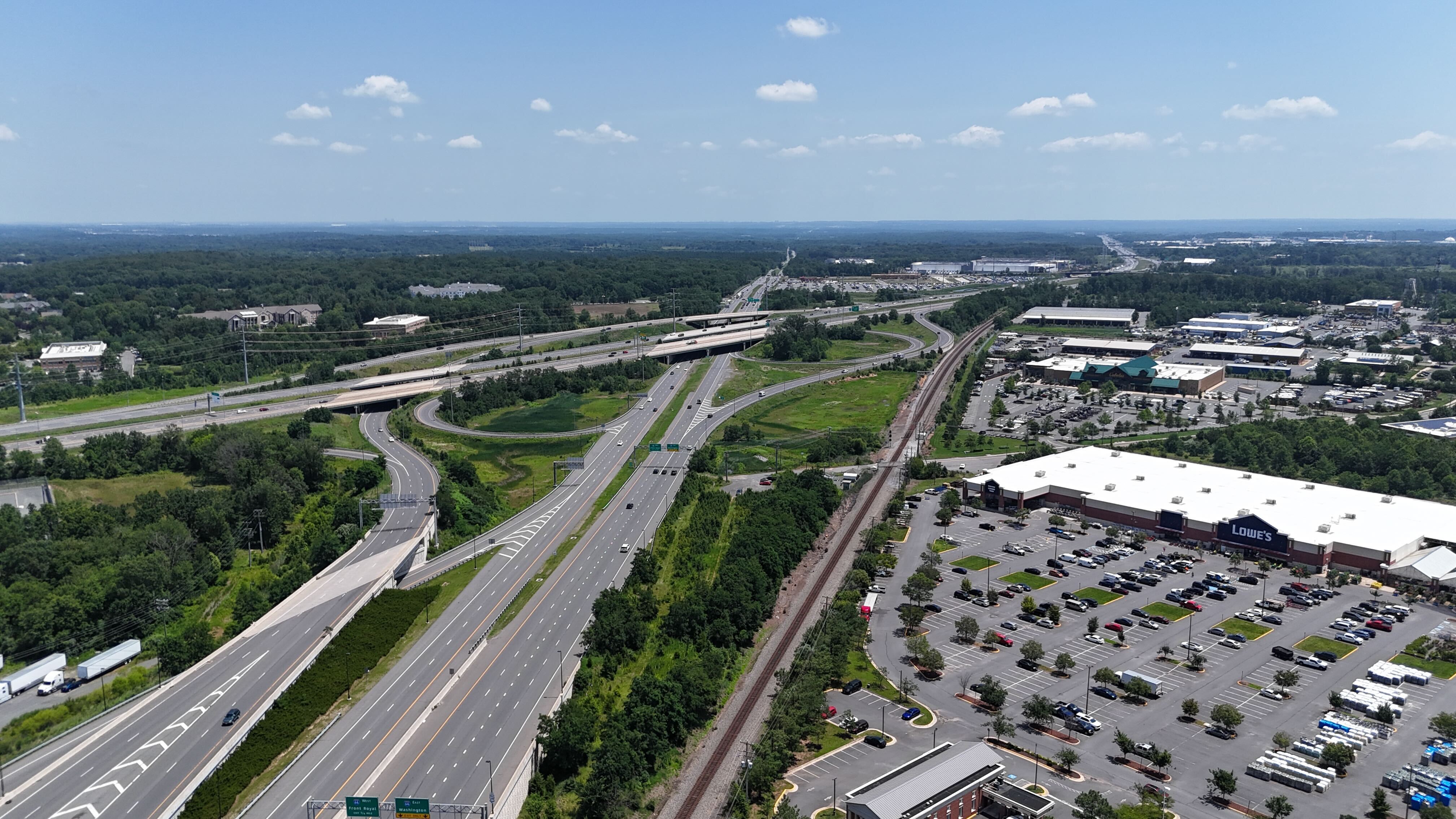 An aerial view of the Lowe's home improvement store and the I-66 interchange in Gainesville, Virginia, showing the highway, railroad tracks, and surrounding commercial area.