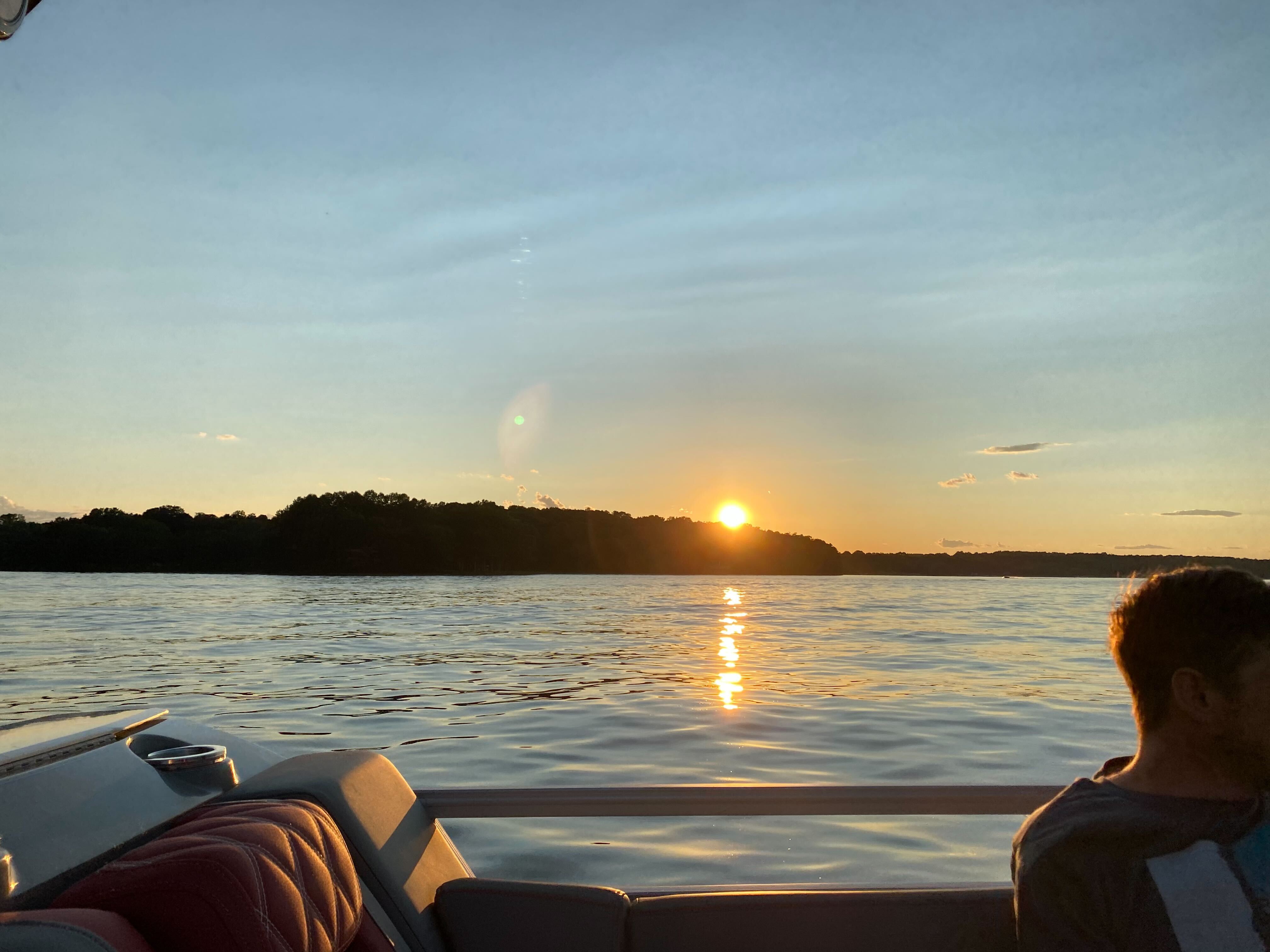 A beautiful sunset over Lake Anna in Virginia, with the sun reflecting on the water, as seen from a boat.