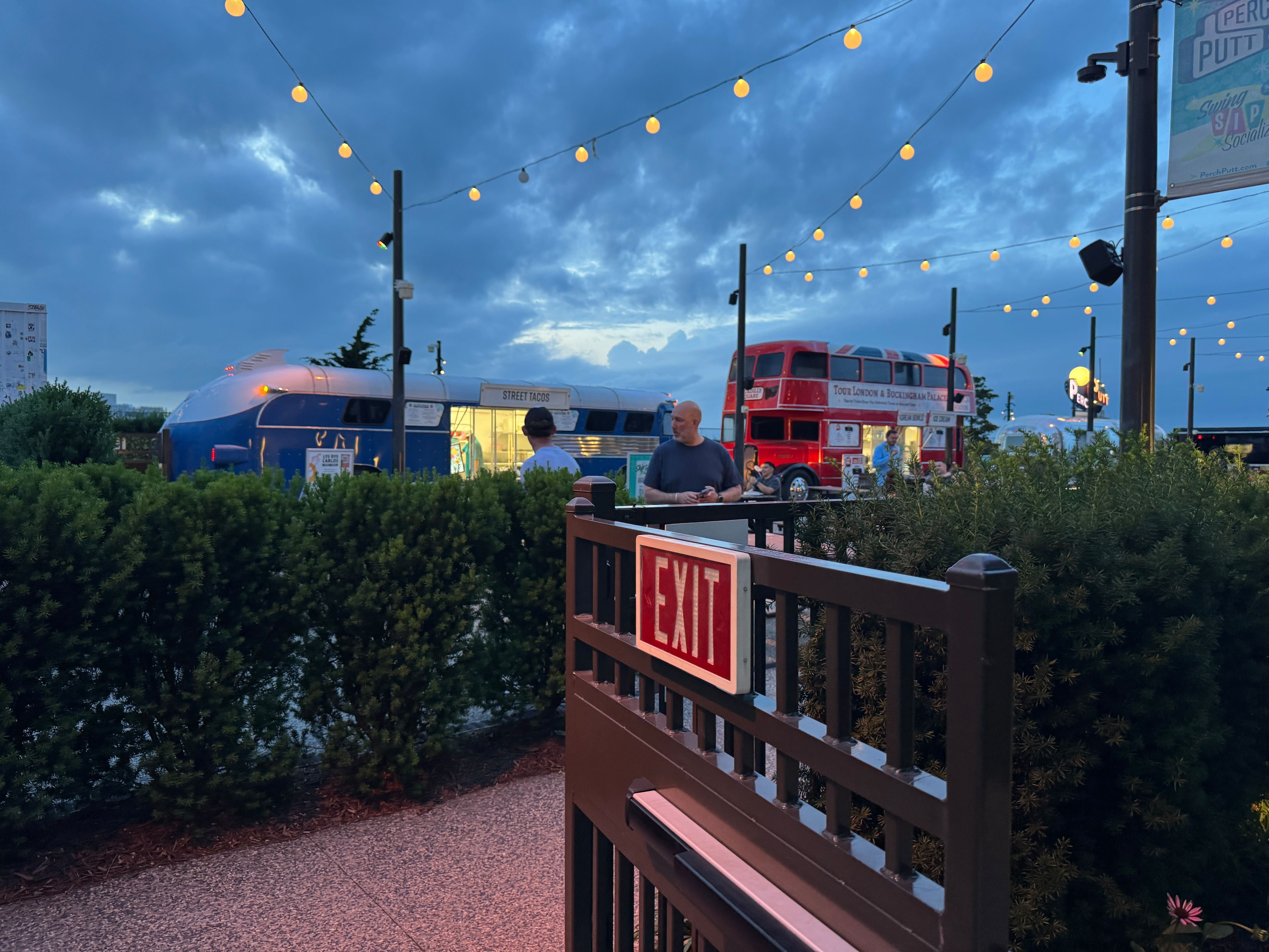 The vintage double-decker bus and Airstream trailer food trucks operating at The Perch in Tysons at night.