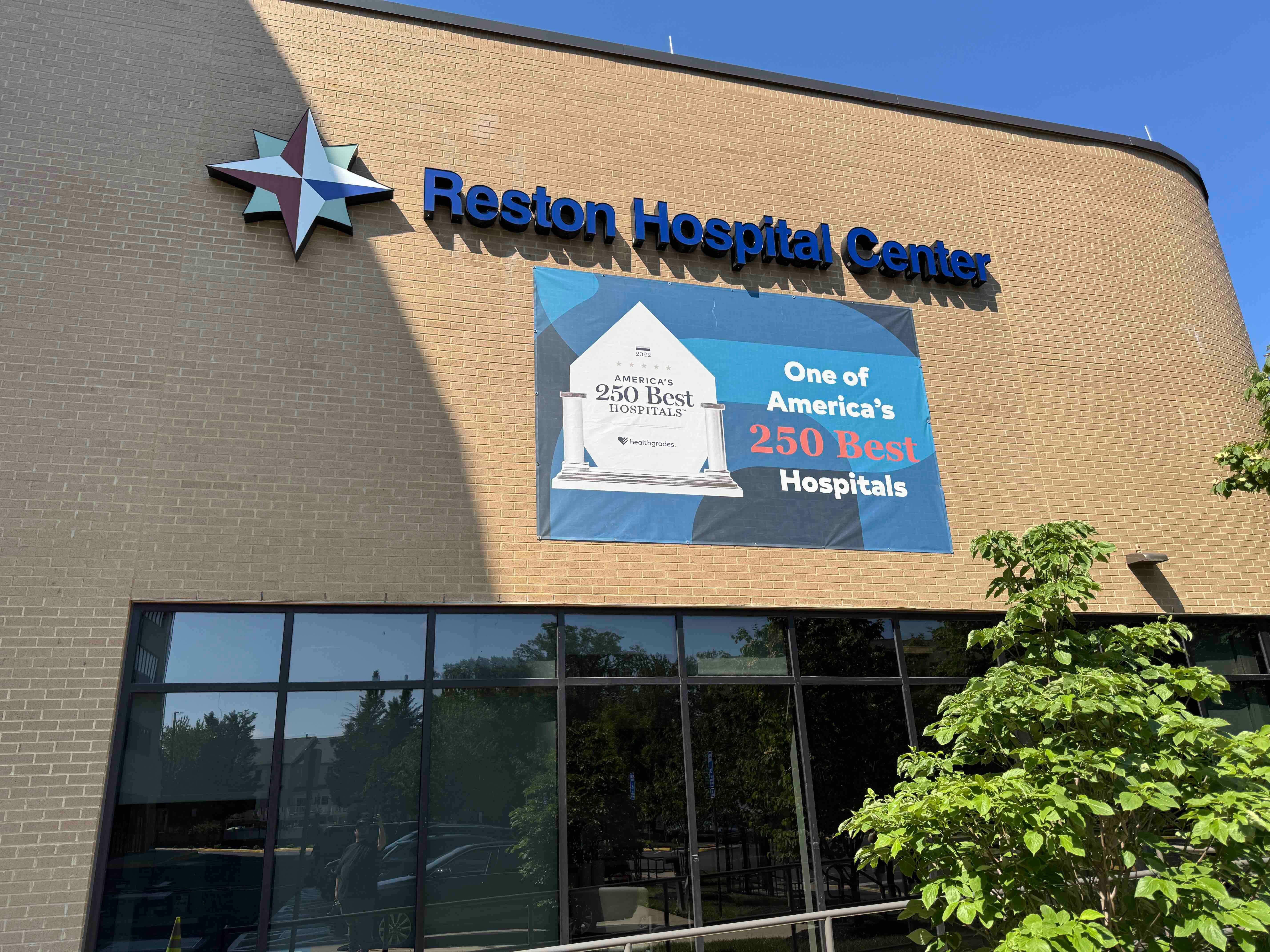 Close-up of the Reston Hospital Center entrance sign and a large banner announcing its Healthgrades award as "One of America's 250 Best Hospitals."