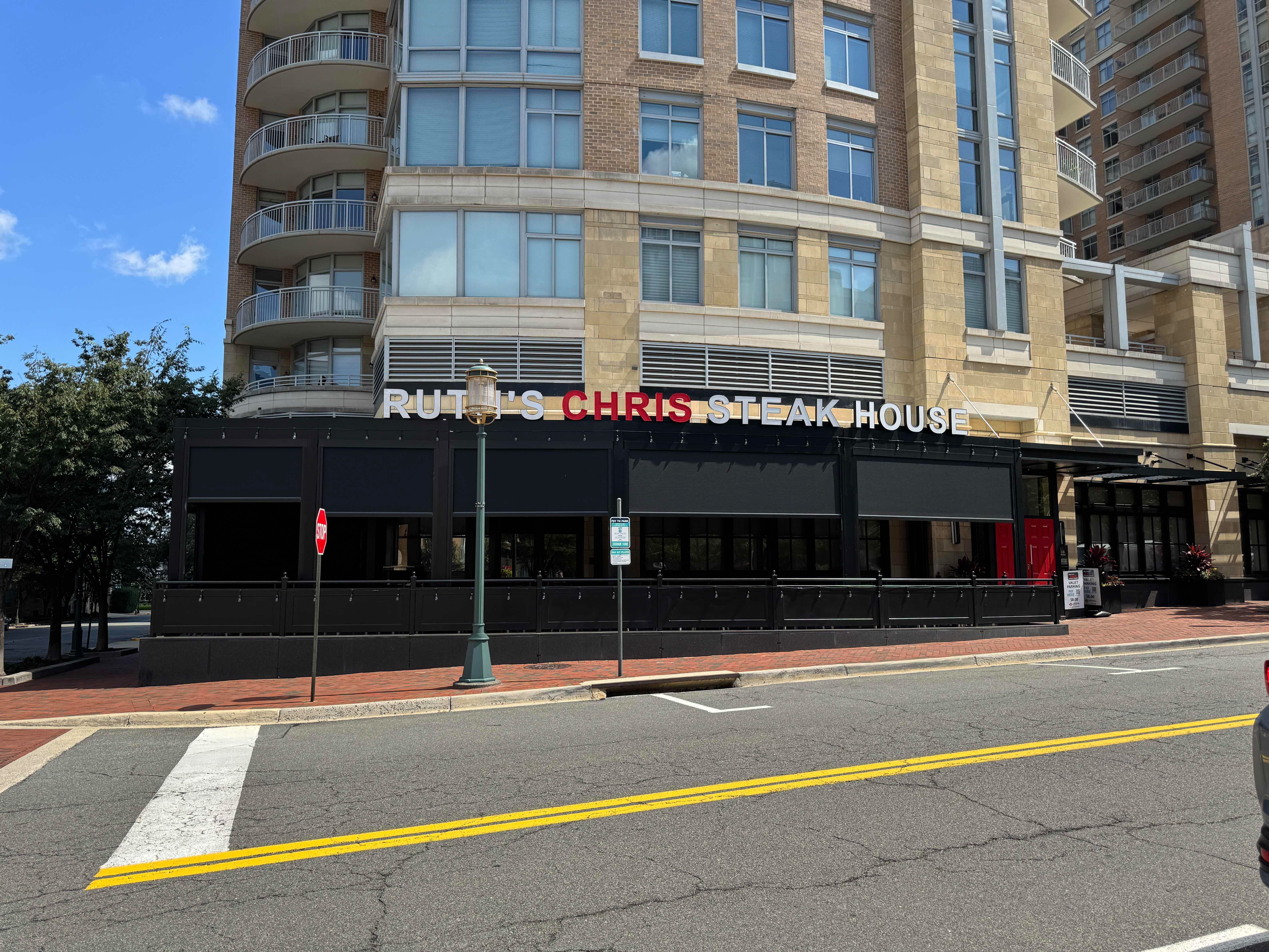 Street-level view of the Ruth's Chris Steak House exterior in Reston Town Center, showing the black awning and signage on the ground floor of a multi-story building.