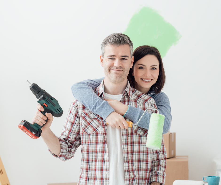 Couple, one holding a drill the other holding a paint roller