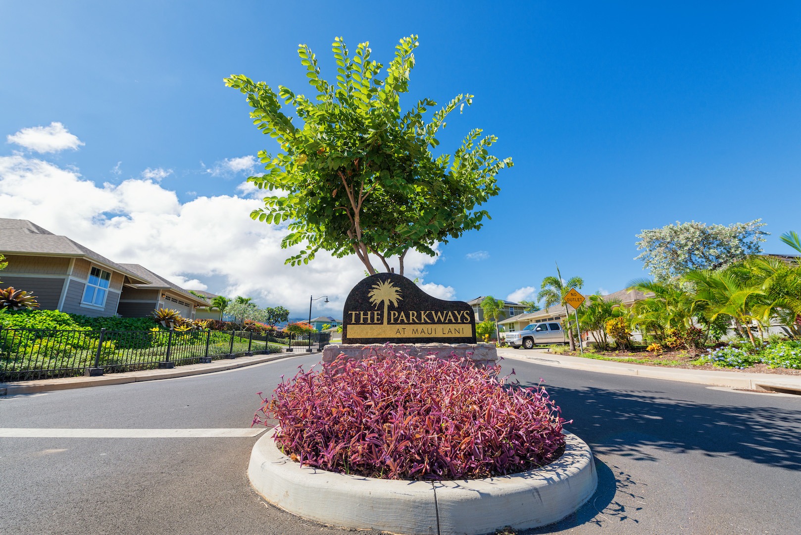 Entrance sign for The Parkways at Maui Lani neighborhood in Kahului, Maui with landscaped streets, tropical plants, modern homes, and bright blue skies.
