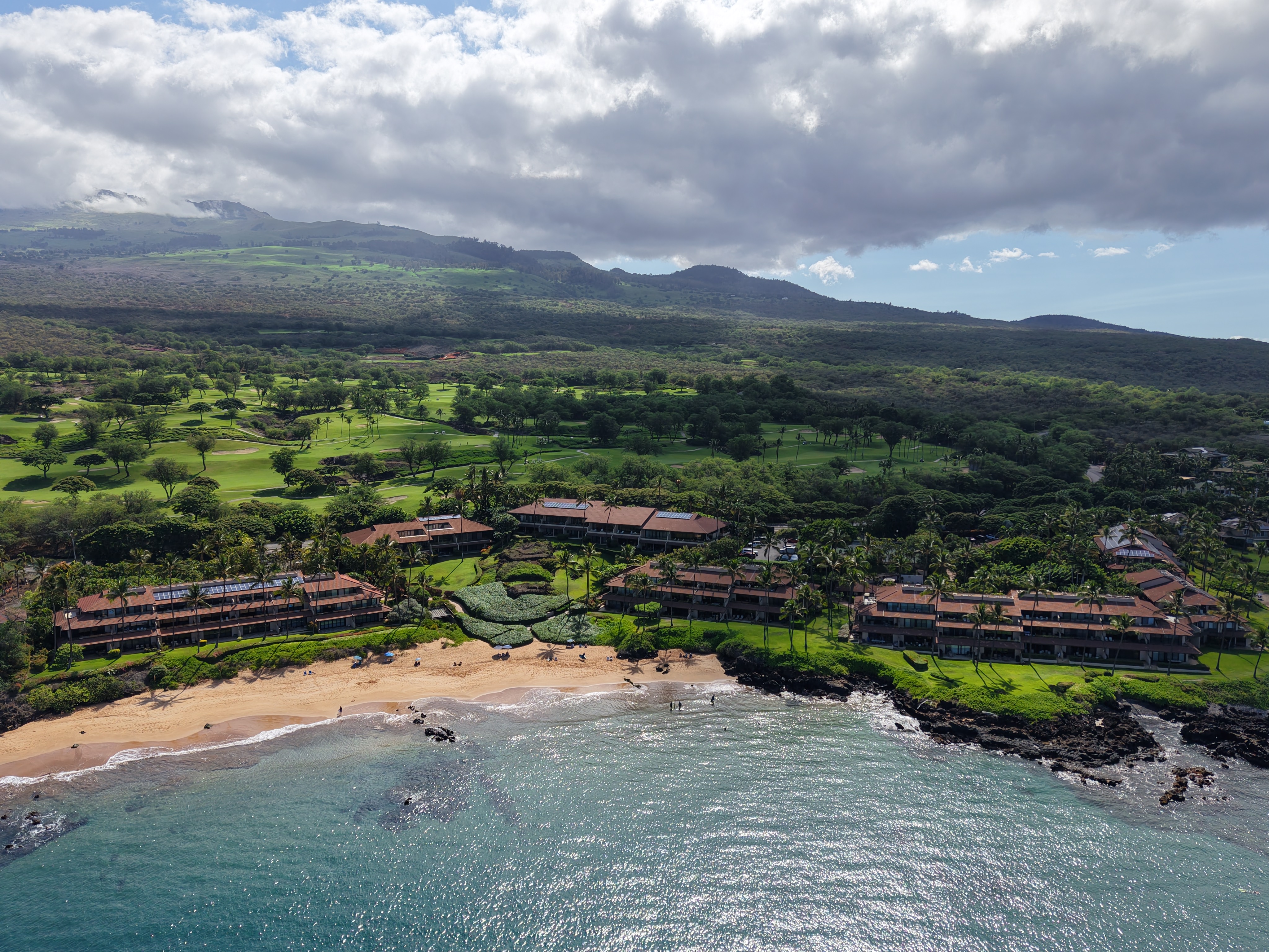 Sunset view from a South Maui condo balcony overlooking the ocean and palm trees