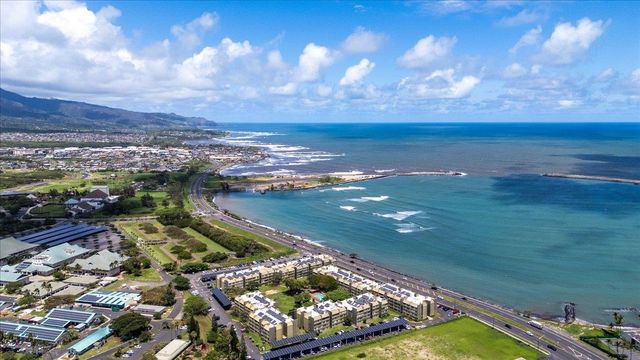 Aerial view of Maui’s South Shore coastline featuring beachfront condo communities, blue Pacific Ocean water, coastal roads, and mountain views under a sunny sky in Kahului, Maui.