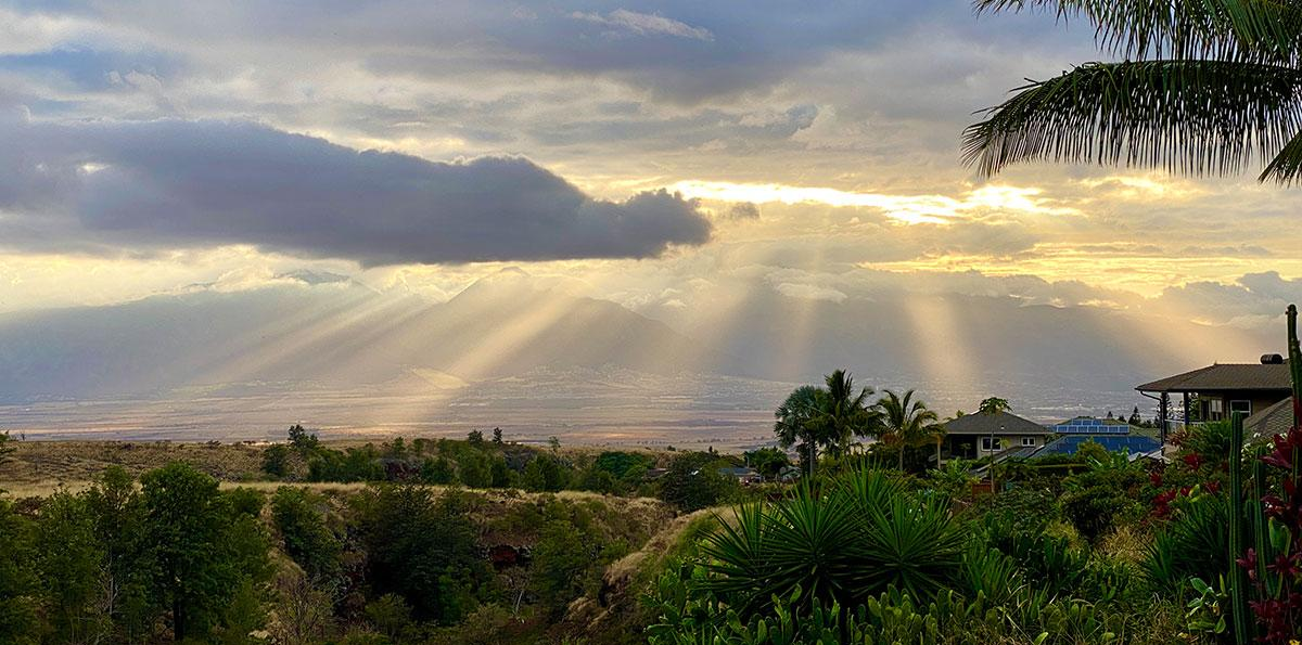 Sun rays shining across Central Maui from a residential neighborhood in Pukalani, showcasing the comfortable Upcountry Maui climate and scenic views residents enjoy year-round