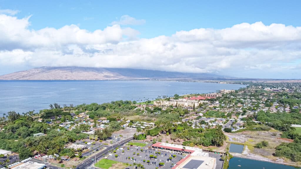 Aerial view of South Kihei, Maui featuring oceanfront neighborhoods, lush greenery, and coastal views with the Pacific Ocean and West Maui Mountains in the background.