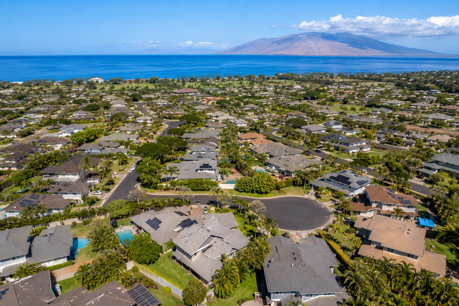 Aerial view of Hale Piilani subdivision in North Kihei Maui showing single-family homes with private lots, cul-de-sac streets, tropical landscaping, ocean views, and the West Maui Mountains in the background