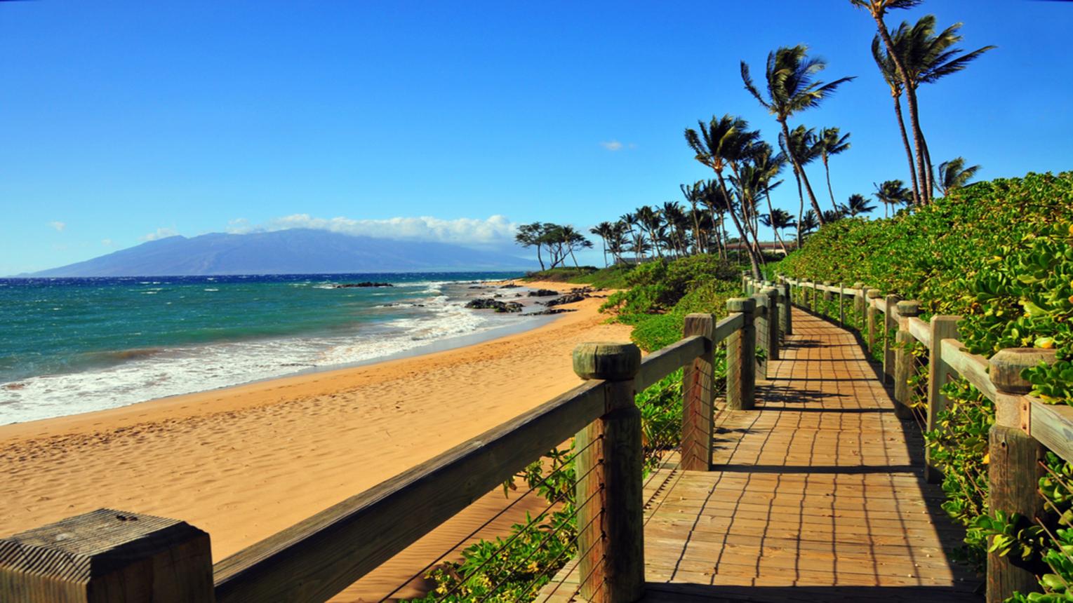 Residents walking along the Wailea Beach Path with ocean views and luxury resorts on Maui's South Shore.