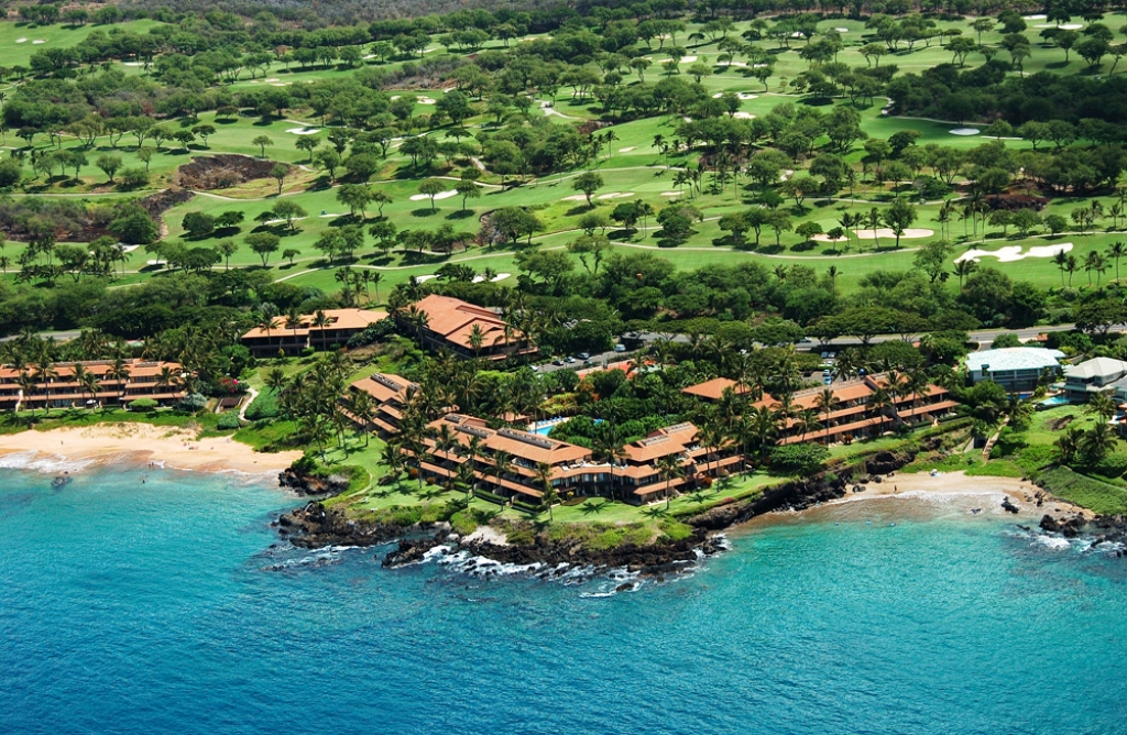 Aerial view of Makena Surf luxury oceanfront condos in Maui, overlooking turquoise waters, sandy beaches, and lush tropical landscaping