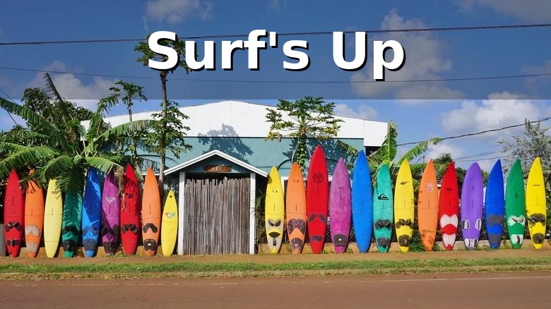 Colorful surfboards lined up along a roadside in Paia on Maui's North Shore with Surf's Up overlay text, showcasing the area's iconic surf culture and laid-back island lifestyle