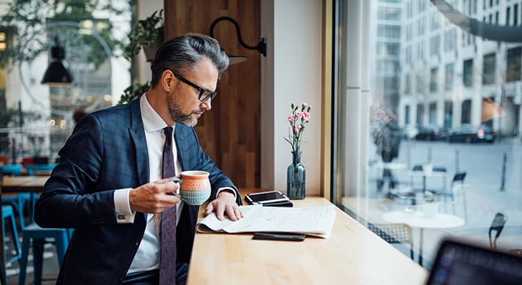 Man reading newspaper at a cafe