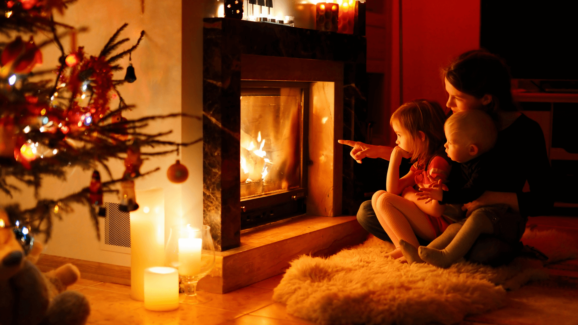 Mother and children sitting beside fireplace with candles