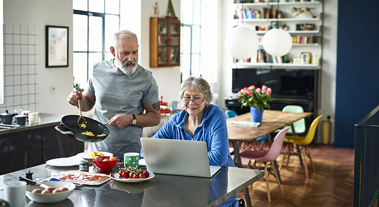 Senior Couple in kitchen looking at computer