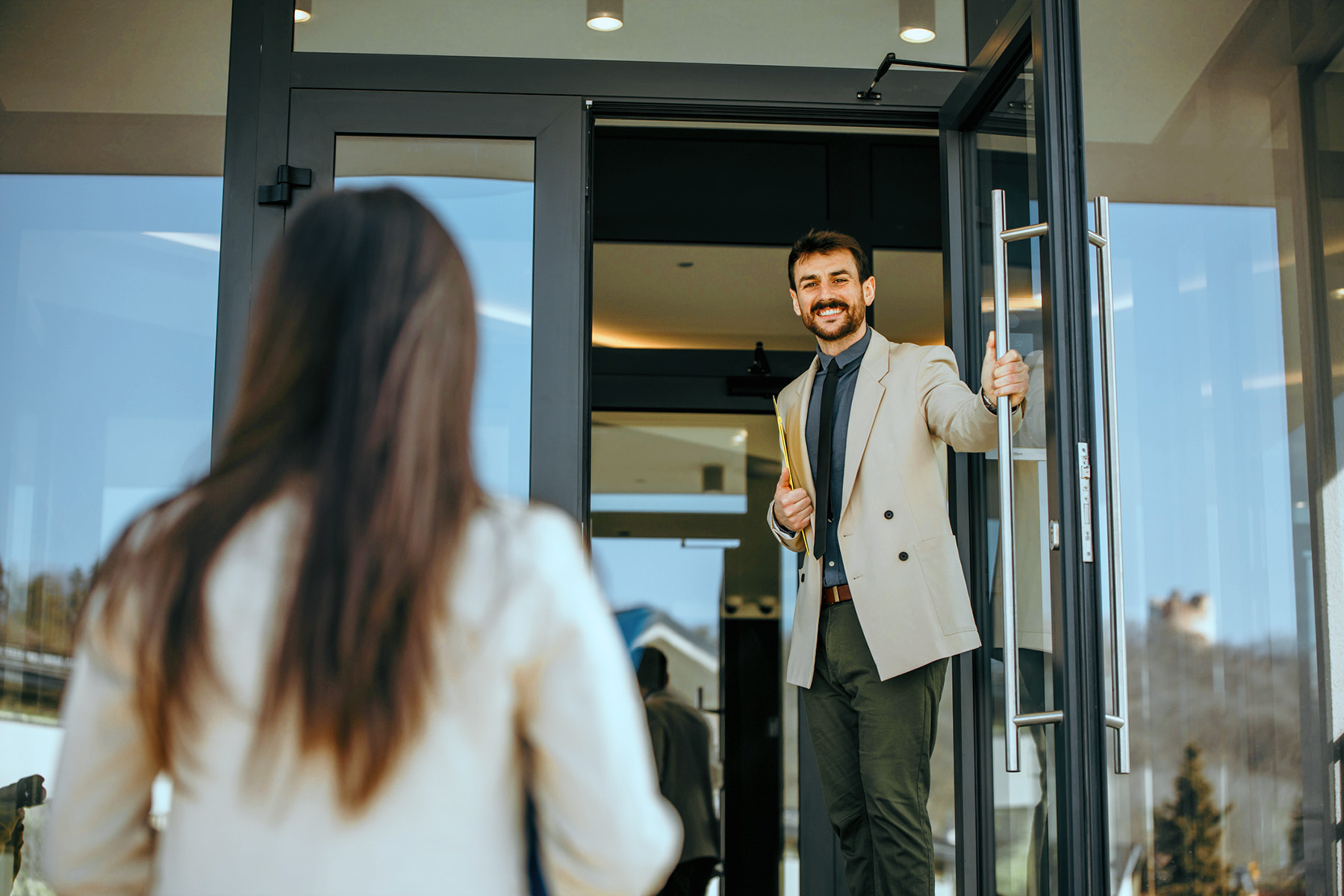 A man holding a door open for a woman entering a building