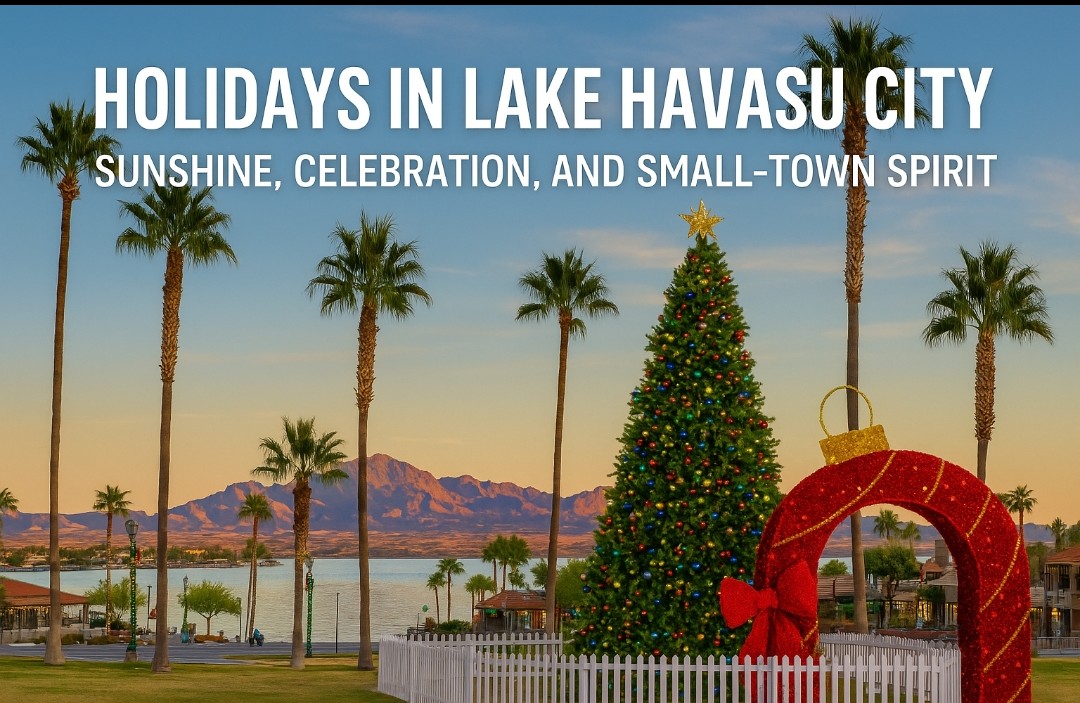 A decorated Christmas tree and large holiday ornament display near the lake in Lake Havasu City, with palm trees, blue water, and mountains in the background during sunset.