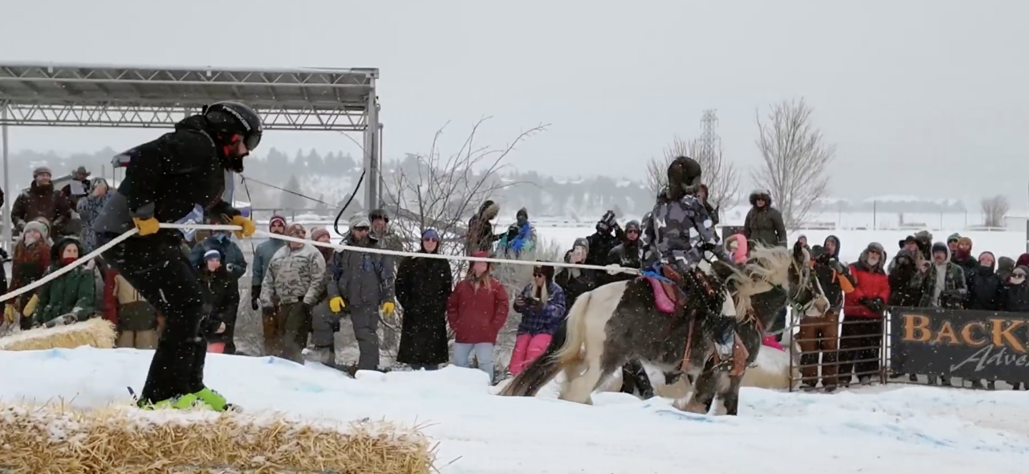 Horse and rider pulling a skier through the skijoring course at the Estes Park Events Complex with Rocky Mountain backdrop