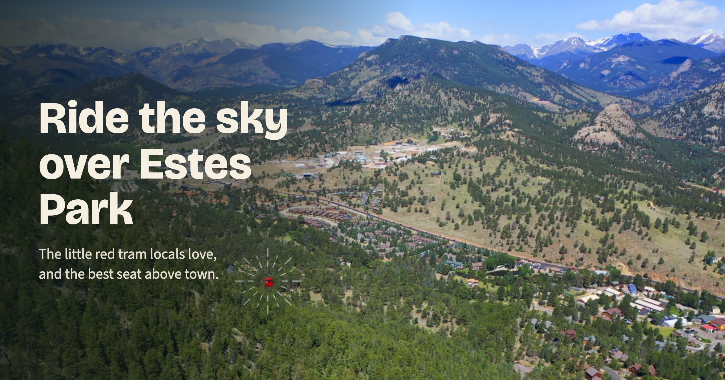 Red Estes Park Aerial Tram car suspended above town, with Rocky Mountain National Park peaks in the background