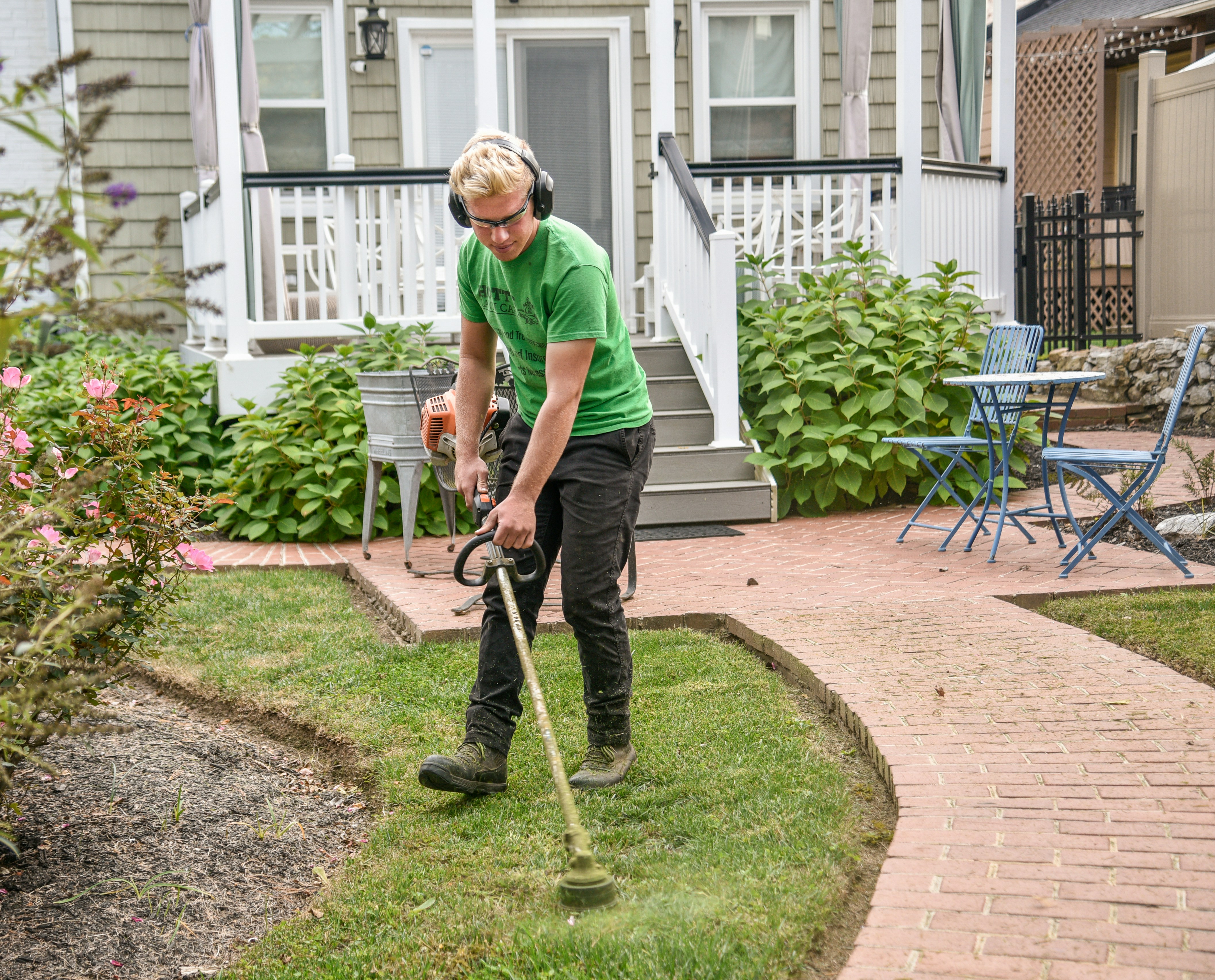 man beautifully landscapes backyard featuring green lawn and growing plants