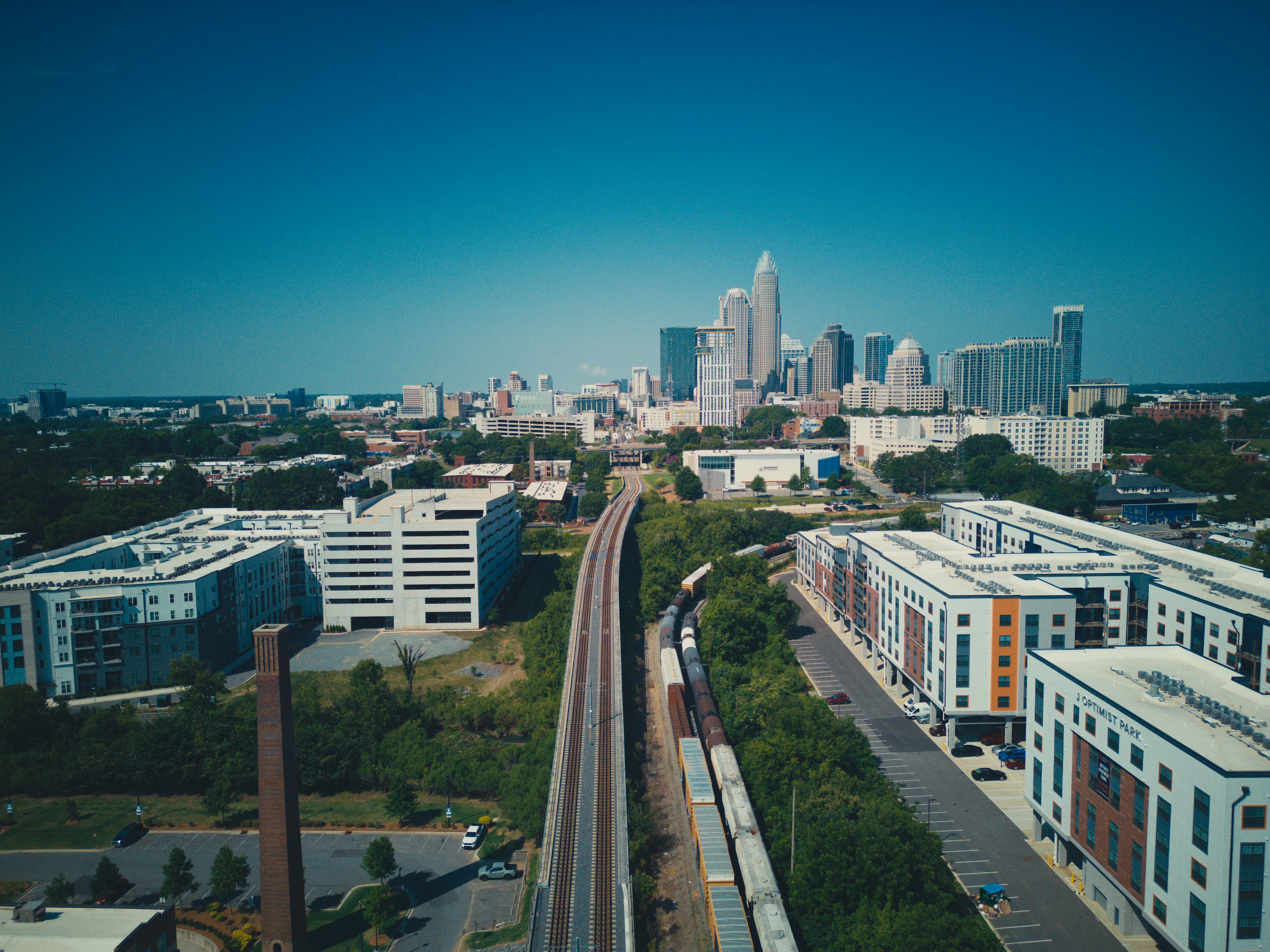 Aerial view of a train on the tracks in NoDa, Charlotte, with the uptown skyline