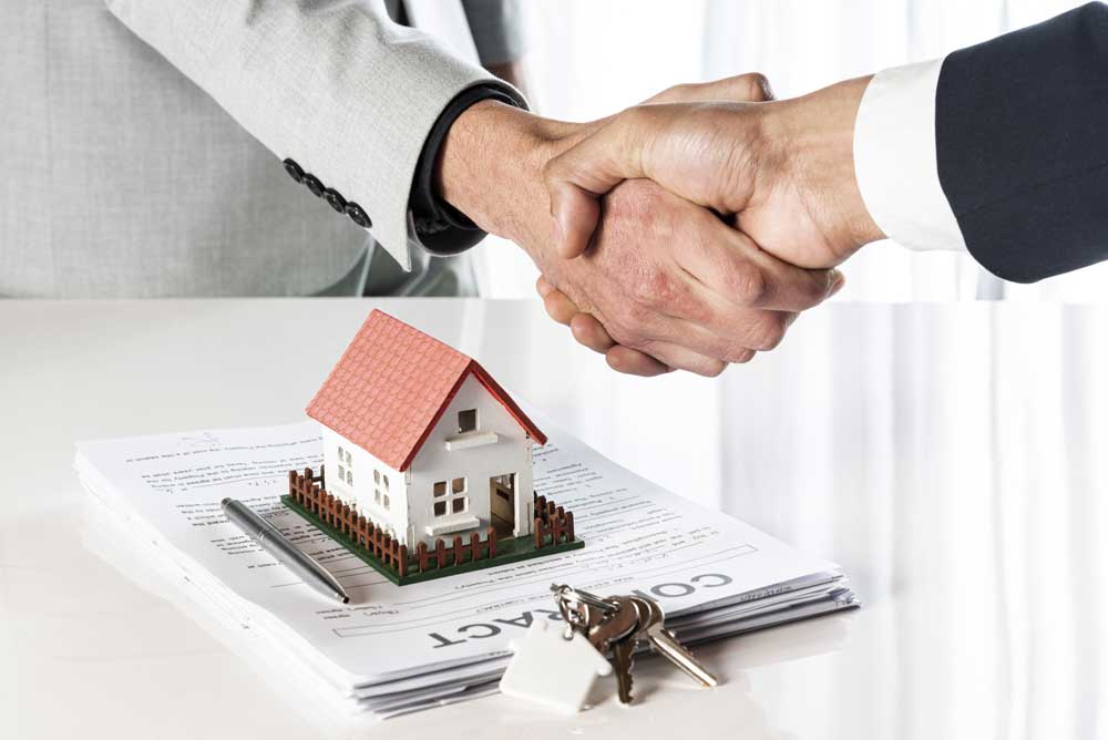 Two people in handshaking over a home purchase contract making a deal
