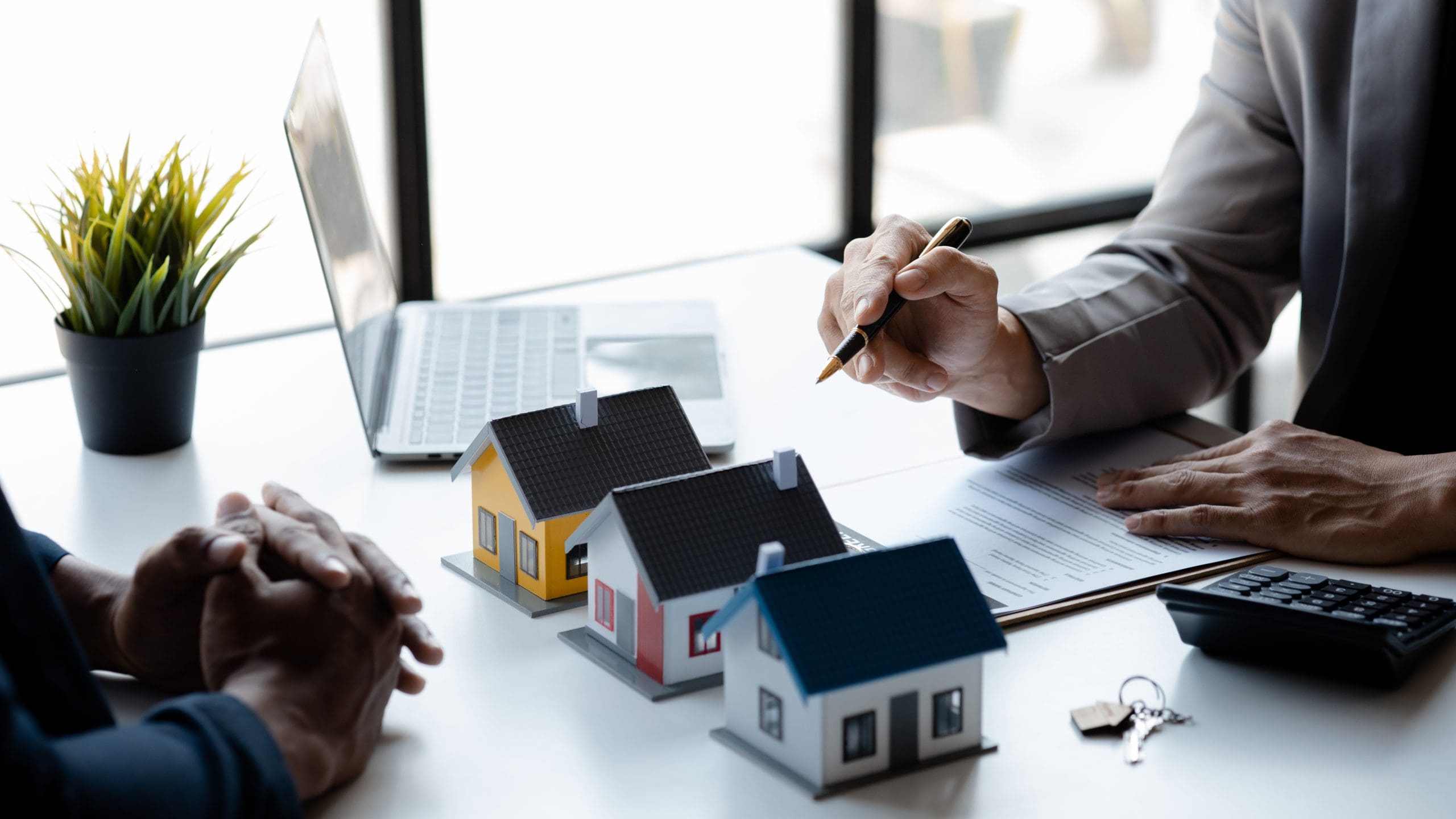 Agent pointing to 3 homes on desk